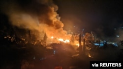 FILE - A fire burns at the migrant camp on the island of Samos, Greece, April 26, 2020.