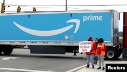 People hold a banner at the Amazon facility as members of a congressional delegation arrive to show their support for workers who voted on whether to unionize, in Bessemer, Alabama, March 5, 2021