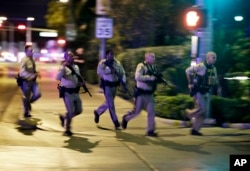 Police run to cover at the scene of a shooting near the Mandalay Bay resort and casino on the Las Vegas Strip, Oct. 1, 2017, in Las Vegas.