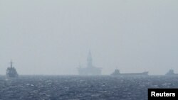 FILE - Ships and an oil rig, center, which China calls Haiyang Shiyou 981, and Vietnam refers to as Hai Duong 981, is seen in the South China Sea, off the shore of Vietnam, May 14, 2014.