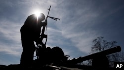 A Ukrainian soldier stands atop a military vehicle near Artemivsk, eastern Ukraine, Monday, Feb. 23, 2015.