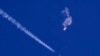 Sisa-sisa balon mata-mata China melayang di atas Samudera Atlantik, tak jauh dari pantai Carolina Selatan, dengan sebuah jet tempur dan jejaknya terlihat di bawahnya, 4 Februari 2023. (Foto: via AP)