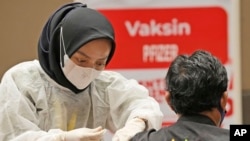 Petugas medis memberikan suntikan booster vaksin COVID-19 Pfizer kepada seorang pria di pusat vaksinasi di Jakarta, Selasa, 18 Januari 2022. (Foto: AP)