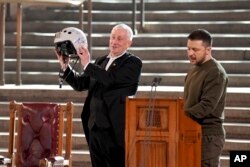 Speaker of the House of Commons, Sir Lindsay Hoyle, left, holds the helmet of one of the most successful Ukrainian pilots, presented to him by Ukrainian President Volodymyr Zelenskyy in Westminster Hall, London, Feb. 8, 2023.