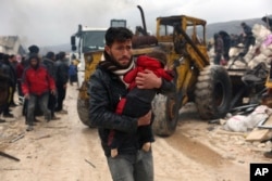 Seorang pria membawa jenazah korban gempa di Desa Besnia dekat perbatasan Turki, Provinsi Idlib, Suriah, Senin, 6 Februari 2023. (Foto: AP)
