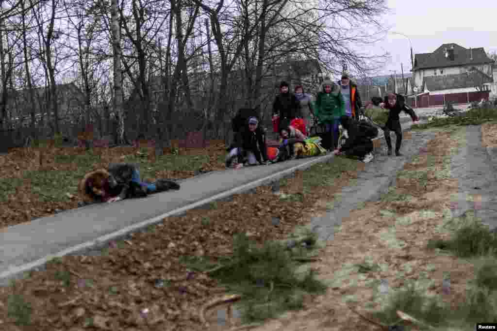 Local residents run for cover as they escape from the town of Irpin, after heavy shelling by Russian troops, March 6, 2022.