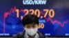 A currency trader walks near the screen showing the foreign exchange rate between U.S. dollar and South Korean won at a foreign exchange dealing room in Seoul, South Korea, Monday, March 7, 2022. (AP Photo/Lee Jin-man)