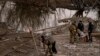 Seorang tentara Ukraina menggendong seorang perempuan lansia saat hendak menyeberangi sungai Irpin di pinggiran Kyiv, Ukraina, Senin, 7 Maret 2022. (AP/Emilio Morenatti)