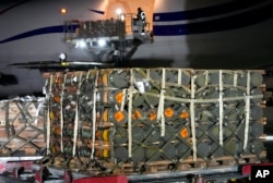 Pekerja membongkar kiriman bantuan militer yang dikirim sebagai bagian dari bantuan keamanan Amerika Serikat ke Ukraina, di Bandara Boryspil, di luar Kyiv, Ukraina, 25 Januari 2022. (Foto: AP)
