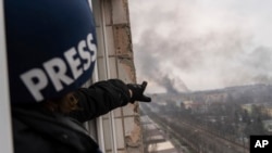 Press photographer Evgeniy Maloletka points at smoke rising after an airstrike on a maternity hospital, in Mariupol, Ukraine, March 9, 2022.