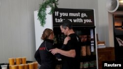 Amy and Chris Hillyard, owners of Farley's East cafe that closed due to the financial crisis caused by COVID-19, embrace at the cafe in Oakland, Calif., March 18, 2020.