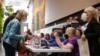 FILE - Poll workers help voters check in at Lincoln Center on the first day of early voting in New York, Oct. 23, 2021.