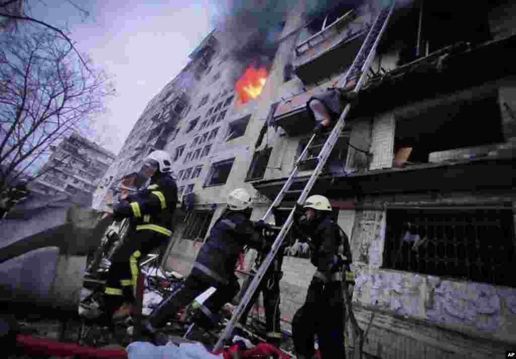 In this photo released by Ukrainian State Emergency Service, firefighters work at an apartment building hit by shelling in Kyiv, March 14, 2022. 