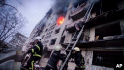 In this photo released by Ukrainian State Emergency Service press service, firefighters work at an apartment building hit by shelling in Kyiv, Ukraine, Monday, March 14, 2022. (Ukrainian State Emergency Service via AP)