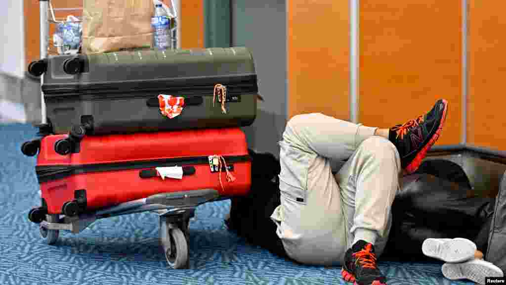 Passengers rest at Vancouver International Airport as it continues to deal with a backlog caused by a winter storm, in Richmond, British Columbia, Canada, Dec. 22, 2022.