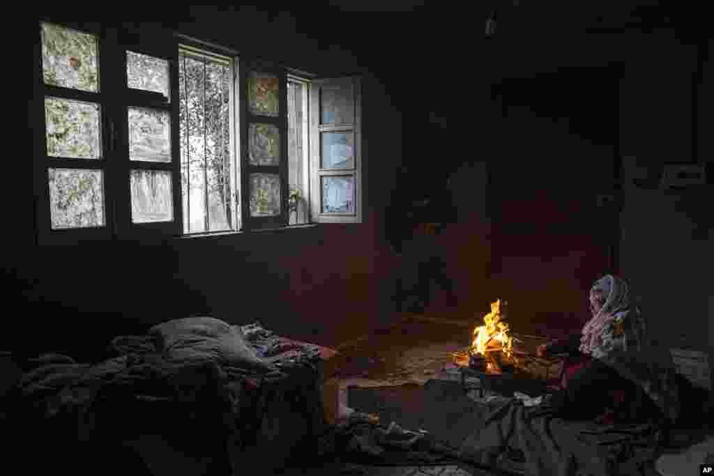 A Palestinian woman warms herself by a fire during a cold weather in Dier al-Balah, central Gaza Strip.