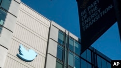 FILE - A Twitter logo hangs outside the company's San Francisco offices on Nov. 1, 2022.
