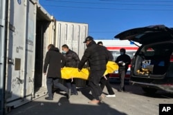 北京一家火葬場的工作人員正在將一具屍體放入冷藏儲存裝置內。（2022年12月17日）