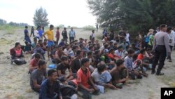 Sejumlah pengungsi Rohingya duduk di pantai selepas kapal yang mereka tumpangi berlabuh di Aceh Besar, pada 8 Januari 2023. (Foto: AP/Irwandi)