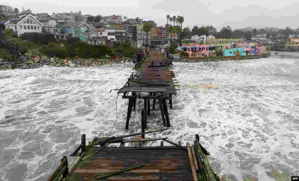This aerial view shows a damaged pier is split in Capitola, California, Jan. 9, 2023. A massive storm called a "bomb cyclone" by meteorologists has arrived and is expected to cause widespread flooding throughout the state. 
