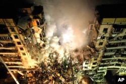 Emergency workers clear the rubble after a Russian rocket hit a multistory building leaving many people under debris in the southeastern city of Dnipro, Ukraine, Jan. 14, 2023.
