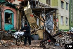 Seorang penduduk setempat mendorong sepedanya melewati perangkap tank dan puing-puing, menyusuri jalan di Bakhmut, wilayah Donetsk, 6 Januari 2023, di tengah invasi Rusia ke Ukraina. (Foto: AFP)