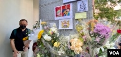 英国驻港总领事馆大楼的支柱上贴满悼念女皇的鲜花和心意卡，有手持鲜花排队等候进入领事馆签署吊唁册的市民神情哀伤 (美国之音/汤慧云)