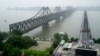 FILE - Visitors cross the Yalu River Broken Bridge, right, next to the Friendship Bridge connecting China and North Korea in Dandong China, Sept. 9, 2017. North Korea and China resumed freight train service, Sept. 26, 2022, after a five-month hiatus, Sout
