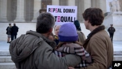 FILE - In this March 27, 2013, file photo a protester holds up a sign that reads "REPEAL DOMA," the Defense of Marriage Act in front of a group from Alabama, clasped in prayer in front of the Supreme Court in Washington, as the court hears arguments on gay marriage.
