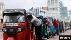 Drivers push auto rickshaws in a line to buy petrol from a fuel station, amid Sri Lanka's economic crisis, in Colombo, Sri Lanka.