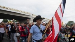 Seorang migran tampak membawa bendera AS ketika ia berjalan bersama rombongan migran lainnya dalam perjalanan dari Tapachula, Meksiko, menuju AS, pada 6 Juni 2022. (Foto: AP/Isabel Mateos)