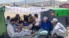 This image provided by Muhammad Arif Sarwari, shows Afghans who fled the Taliban takeover of their country checking their phones at Camp Bondsteel in Kosovo, June 1, 2022. 