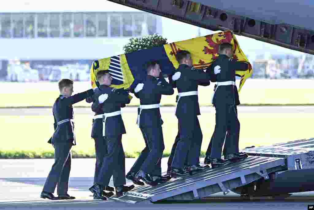 Pallbearers from the Queen's Colour Squadron of the Royal Air Force (RAF) carry the coffin of Queen Elizabeth II, draped in the Royal Standard of Scotland, into a RAF C17 aircraft at Edinburgh airport, Sept 13, 2022, before it is transported to Buckingham Palace in London. 