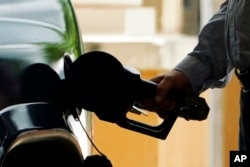 FILE- A customer pumps gas into his vehicle at a Sam's Club in Madison, Miss., May 24, 2022.