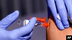 FILE - A patient is given a flu vaccine at a community clinic in Lynwood, Calif., Oct. 28, 2022. A rapidly intensifying flu season is straining some U.S. hospitals already overburdened with patients sick from other respiratory infections.