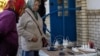 Locals charge their mobile phones with the electricity provided from a generator in front of a shop as there is no electricity in Balakliia, recently liberated by Ukrainian Armed Forces, in Kharkiv region, Sept. 21, 2022. 