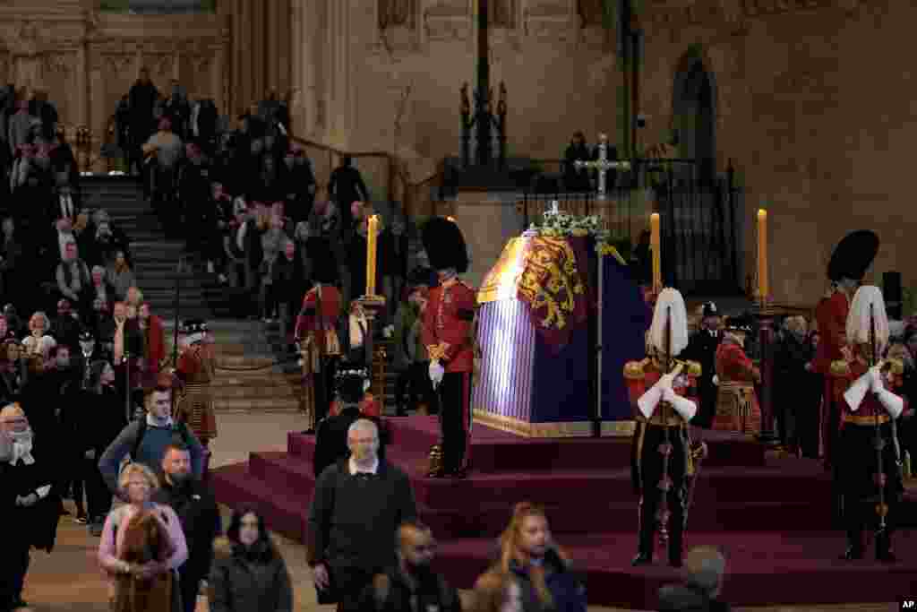A ray of sun shines on the coffin as members of the public file past the coffin of Queen Elizabeth II, draped in the Royal Standard with the Imperial State Crown and the Sovereign's orb and sceptre, lying in state on the catafalque in Westminster Hall in London, Sept. 18, 2022.