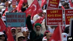 FILE - Demonstrators hold banners that read, "Law for the development of the spirit and moral" and "LGBTQ, remove your dirty hand from our children" during an anti LGBTQ protest in Fatih district of Istanbul, Sept. 18, 2022.