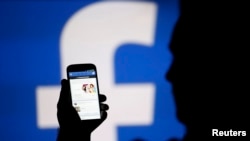 Silhouette seorang pria dengan latar belakang layar video yang menampilkan logo Facebook dalam foto ilustrasi yang diambil di kota Zenica, Bosnia tengah, tanggal 14 Agustus 2013 (foto: REUTERS/Dado Ruvic/Foto Arsip)