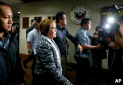 FILE - Philippine Senator Leila de Lima, second from left in foreground, is escorted out of the Philippine Senate premises following a news conference, Feb. 21, 2017, in suburban Pasay city, south of Manila, after the Philippine justice secretary filed charges against her.