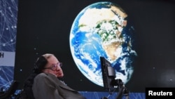 Pakar ilmu fisika teoritis, Stephen Hawking duduk di atas panggung saat pengumuman inisiatif Starshot dengan investor Yuri Milner di New York, 12 April 2016. (Foto: dok).