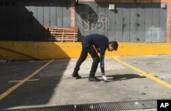 A criminal investigator collects evidence in a parking lot where an allegedly armed drone crashed into a building in Caracas, Venezuela, Sunday, Aug. 5, 2018.