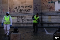 Radnici čiste oko Trijumfalne kapije dan nakon demonstracija žutih prsluka zbog podizanja cena goriva i životnih troškova, 2. decembra 2018. u Parizu. Grafit na spomeniku znači "žuti prsluci će trijumfovati"