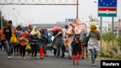 FILE - Migrants walk as they cross the border from Hungary to Nickelsdorf, Austria, Sept. 25, 2015. The refugee issue and Austria preserving its identity were major issues in the country's presidential campaign.