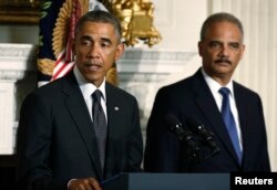 FILE - President Barack Obama, accompanied by Attorney General Eric Holder, speaks in the State Dining Room of the White House, Sept. 25, 2014.