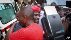 Ugandan pop star Kyagulanyi Ssentamu, better known as Bobi Wine, center, wears a beret and is hugged by a supporter as he gets into an ambulance after leaving the courthouse in Gulu, Uganda, Aug. 27, 2018. 