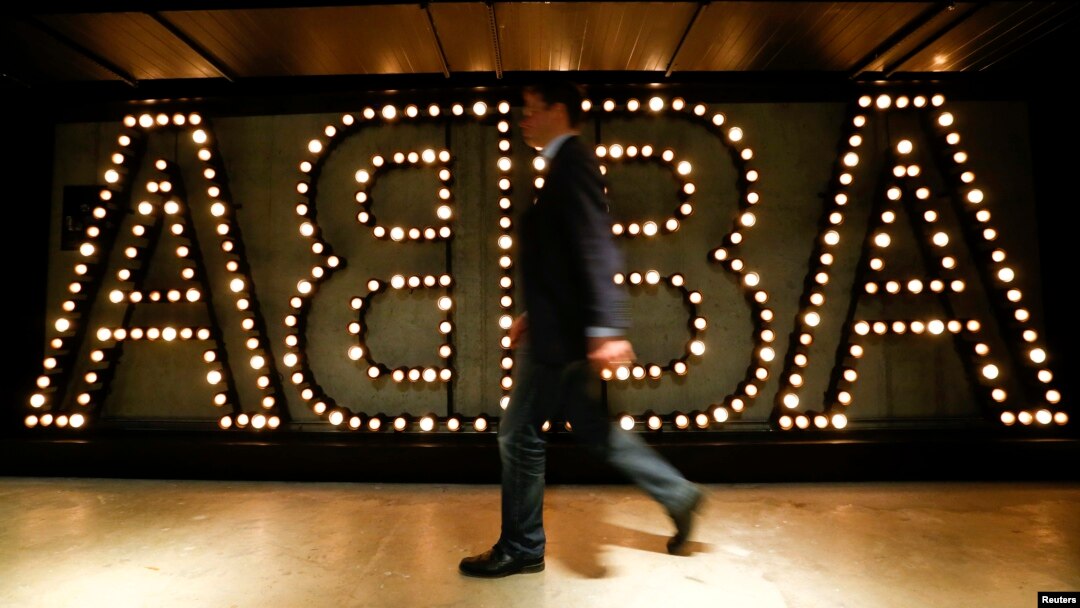 FILE - A man walks past the lit logo of the legendary Swedish pop group ABBA at "ABBA — The Museum" in Stockholm, May 6, 2013. 