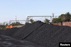 Kereta Transnet Freight Rail terlihat di samping berton-ton batu bara yang ditambang dari tambang Khanye Colliery di dekatnya, di stasiun Bronkhorstspruit, di Bronkhorstspruit, sekitar 90 kilometer timur laut Johannesburg, Afrika Selatan, 26 April 2022. (REUTERS/Siphiwe Sibeko)