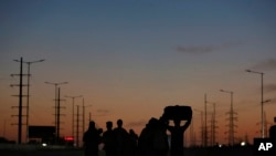 An Indian migrant laborer's family is silhouetted as they make the journey to their village by foot following a lockdown amid concern over spread of coronavirus in New Delhi, India, March 28, 2020.