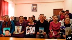 在哈萨克斯坦阿拉木图一个中国哈萨克族人组织的办公室里，人们手举在新疆失踪亲属的照片。（2018年12月7日）